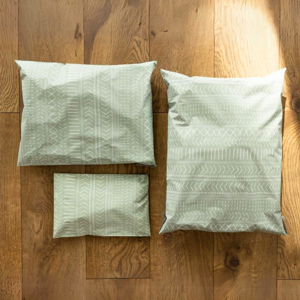 Comparison of 10x13 Green Geo Boho Poly Mailer sizes on a table - 12x15.5, 10x13, and 6x9. Self-sealing plastic shipping envelopes for versatile and stylish small business packaging.