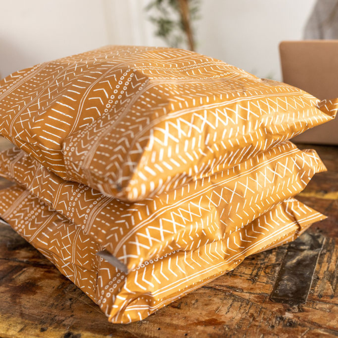 Close-up of Favorite Supplies' Boho Brown Poly Mailers stacked on a table. Showcase of the intricate white block-printed boho line design on the self-sealing plastic shipping envelopes.
