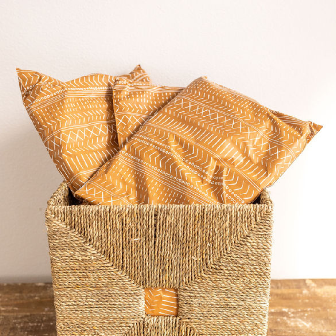 Boho Brown Poly Mailers from Favorite Supplies arranged on a table and neatly stacked in a basket. Ready for shipping with their charming white block-printed boho line design.