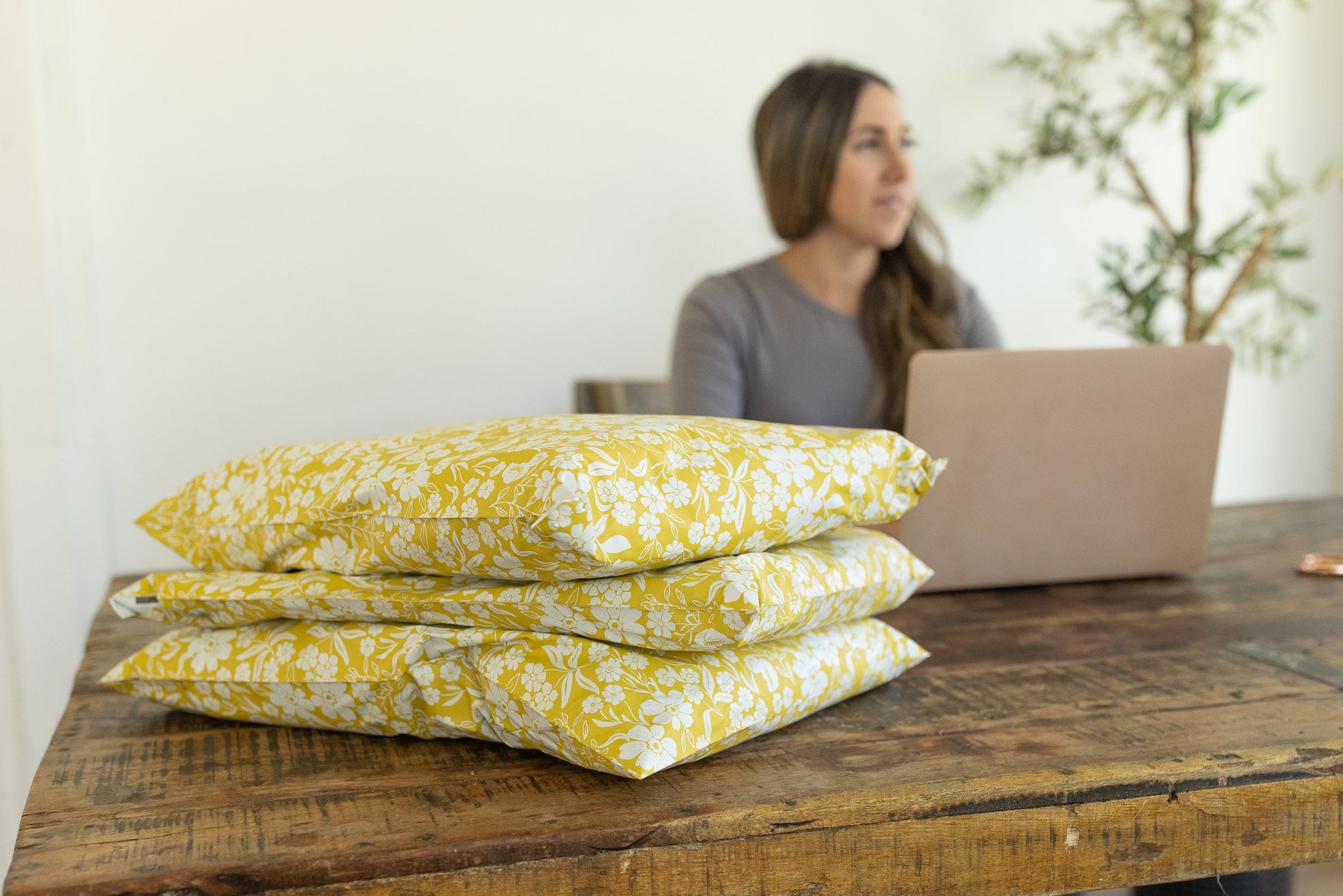 A stack of fulfilled orders, a pretty business brand photo with yellow floral polymailer bags.