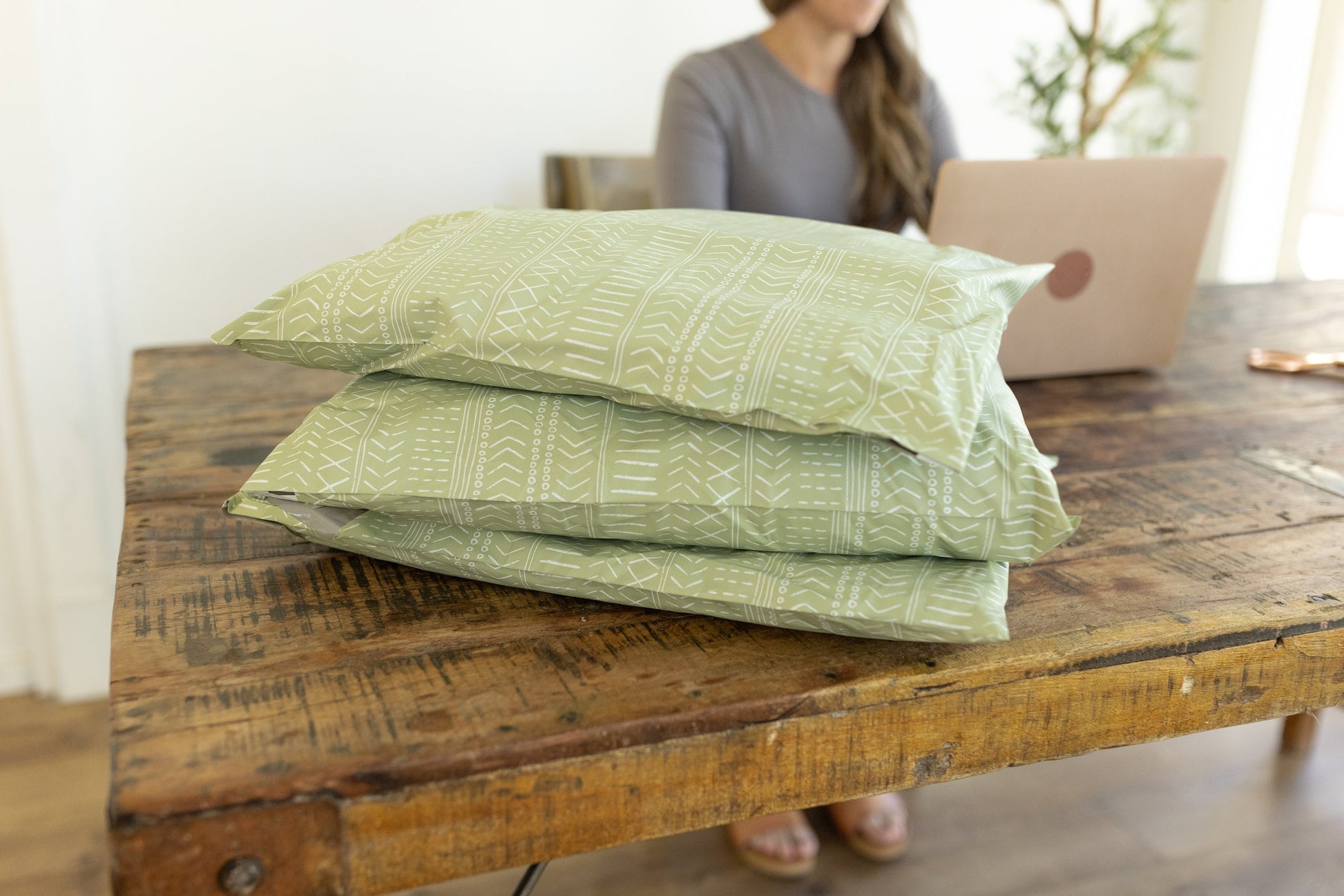 A stack of extra large mailing bags packaged on a wooden desk.